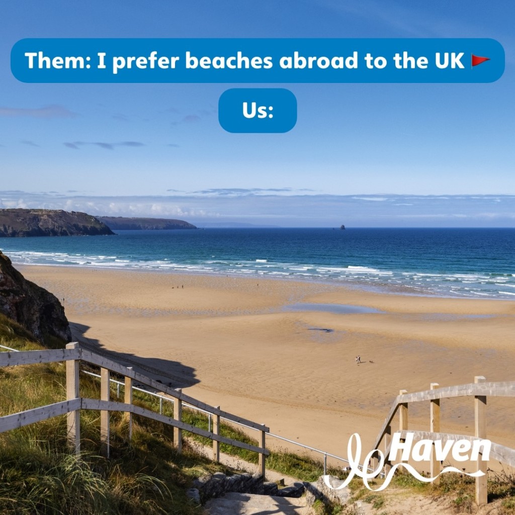 Text reads, "Them: I prefer beaches abroad to the UK. Us:" Image of a beautiful sandy beach in the UK with blue sky and sunshine, and gently rolling waves on the shore. Haven Holidays affiliated with SpookyMrsGreen.com mindful parenting and modern pagan lifestyle blog.